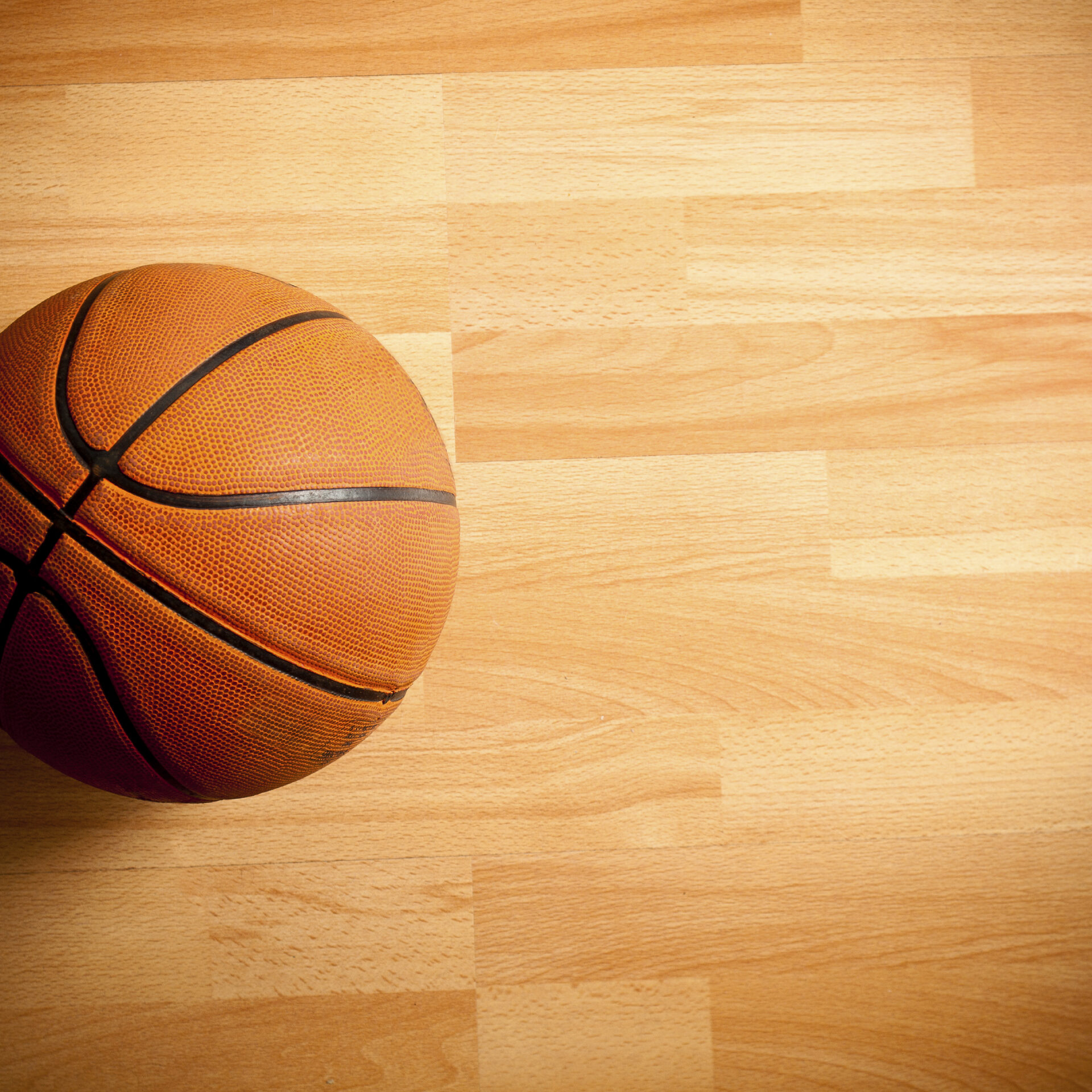 An official orange ball on a hardwood basketball court